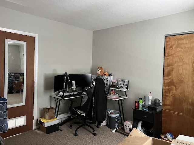 carpeted office featuring a textured ceiling