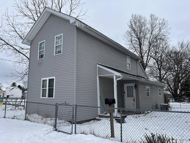 snow covered back of property featuring cooling unit