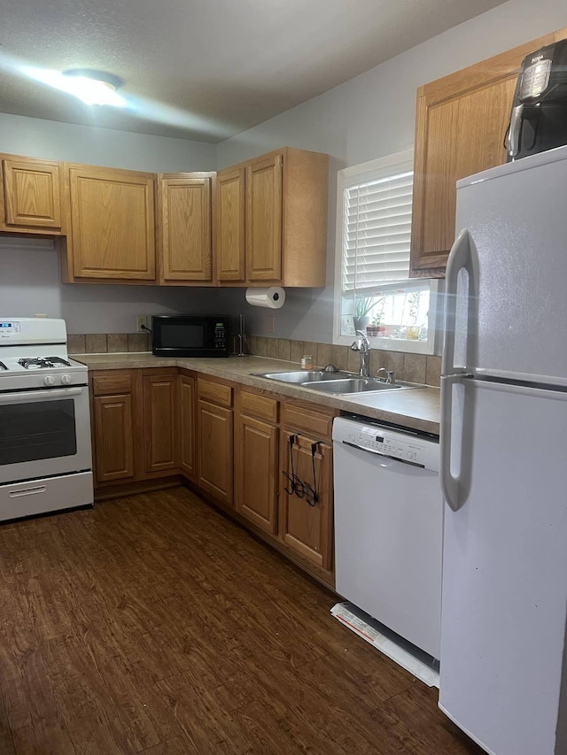 kitchen with white appliances, dark hardwood / wood-style floors, and sink