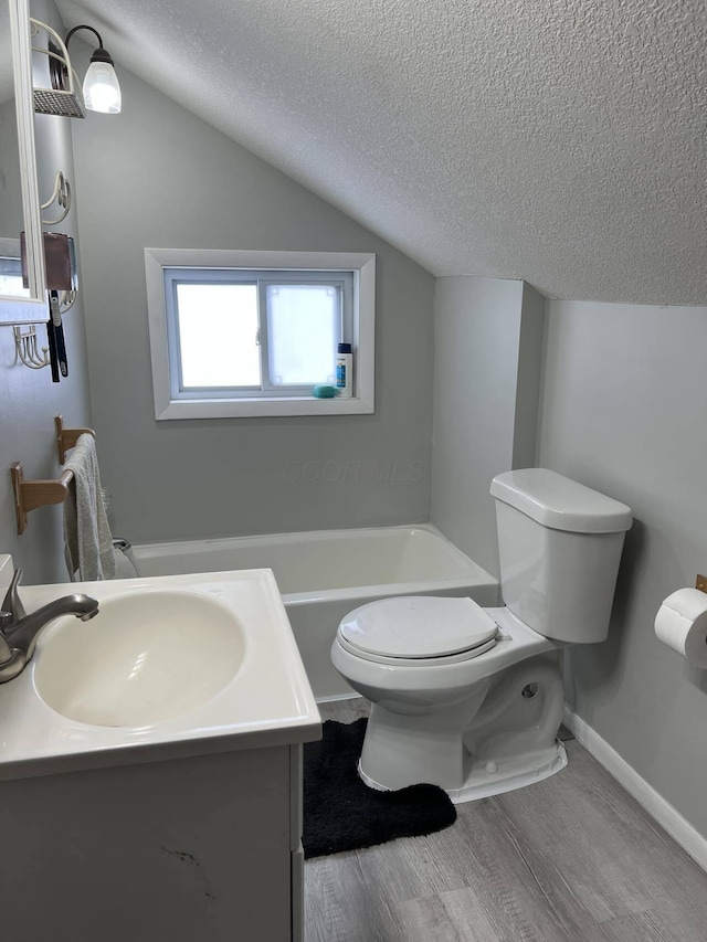 bathroom with toilet, vanity, a textured ceiling, and vaulted ceiling