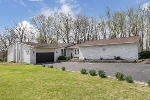 ranch-style home featuring a garage and a front lawn