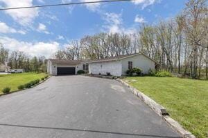 ranch-style home with a garage and a front lawn