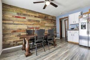 dining room with hardwood / wood-style flooring, ceiling fan, and wooden walls