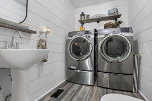 washroom featuring washer and clothes dryer, wood-type flooring, and wooden walls