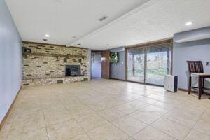 unfurnished living room featuring a stone fireplace and light tile patterned floors