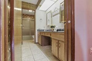 bathroom featuring toilet, vanity, tile patterned floors, and a shower with shower door