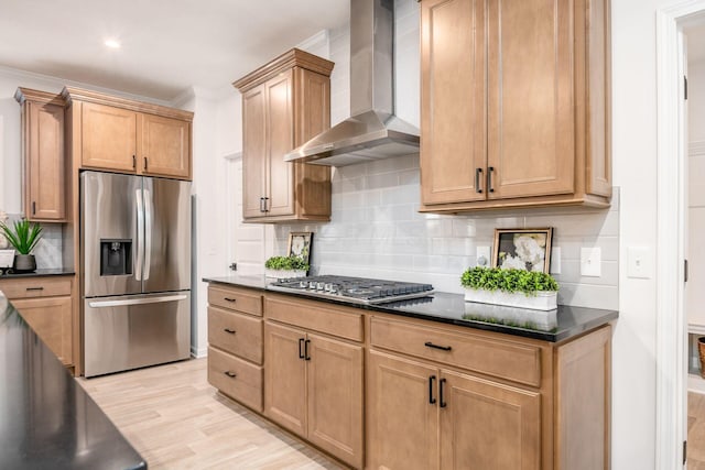 kitchen featuring decorative backsplash, appliances with stainless steel finishes, ornamental molding, wall chimney exhaust hood, and light hardwood / wood-style flooring