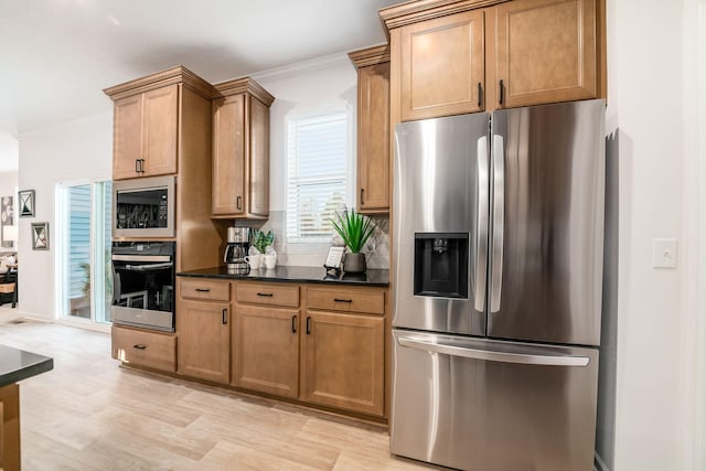 kitchen with light hardwood / wood-style flooring, ornamental molding, and appliances with stainless steel finishes