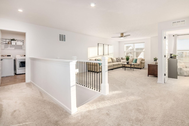 living room with washing machine and dryer, light carpet, plenty of natural light, and ceiling fan