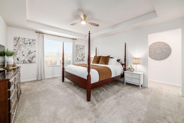 carpeted bedroom featuring ceiling fan and a raised ceiling