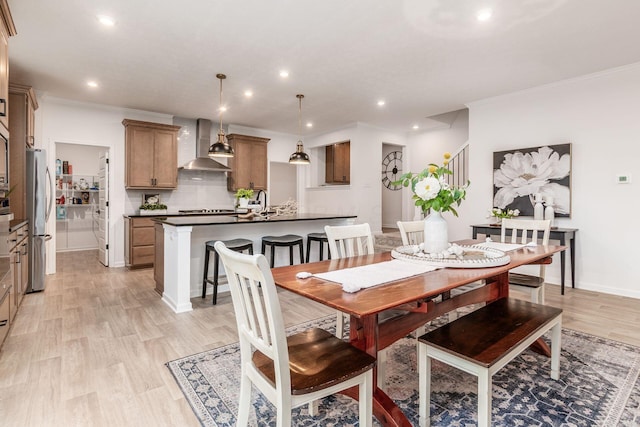 dining space featuring light wood-type flooring and crown molding