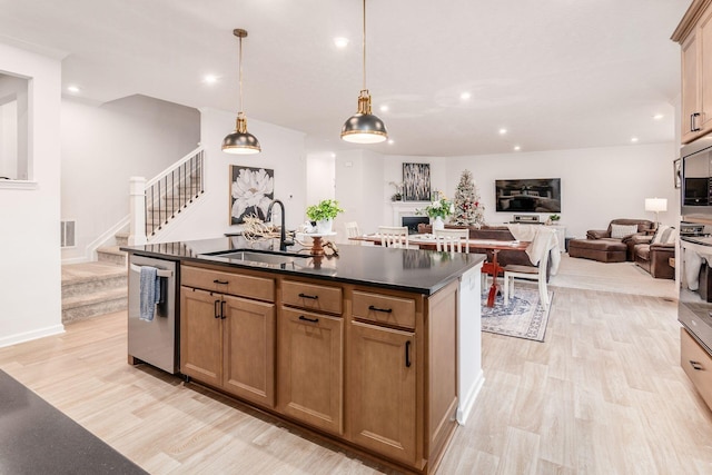 kitchen with dishwasher, a center island with sink, sink, hanging light fixtures, and light hardwood / wood-style flooring