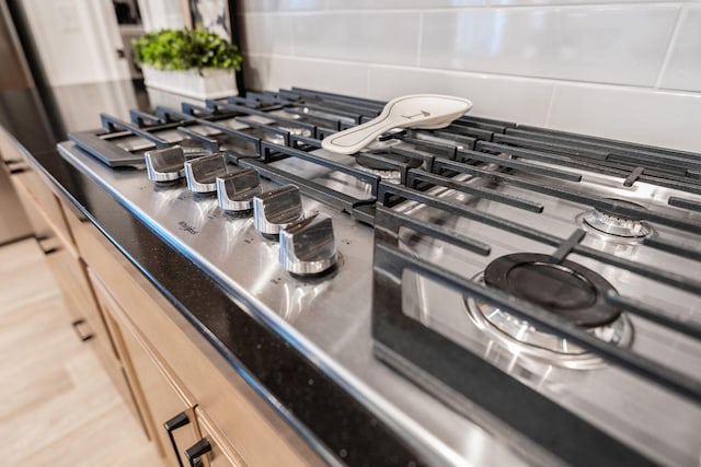 details with light brown cabinetry, hardwood / wood-style flooring, and stainless steel gas cooktop