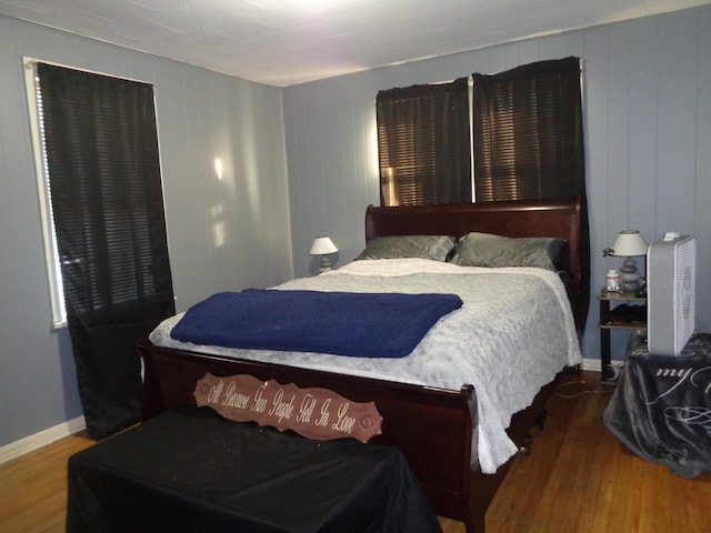 bedroom with wood walls and hardwood / wood-style floors