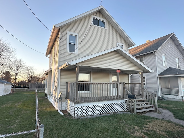 back house at dusk featuring a porch and a yard