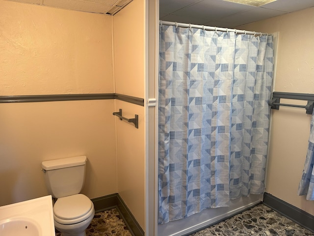 bathroom with a drop ceiling, toilet, and shower / bathtub combination with curtain