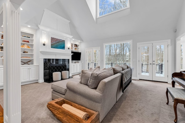 living room with high vaulted ceiling, a high end fireplace, light carpet, built in shelves, and french doors