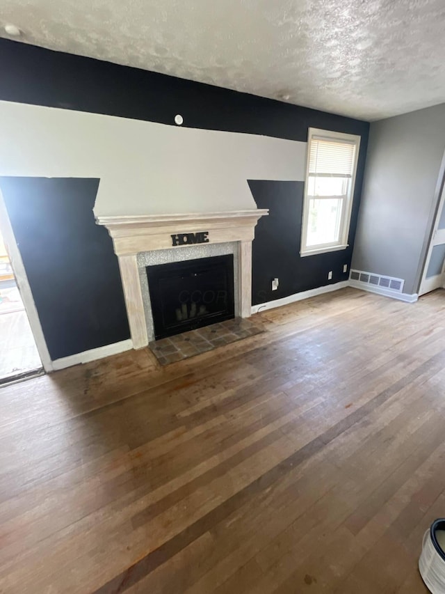 unfurnished living room with a fireplace, a textured ceiling, and hardwood / wood-style flooring