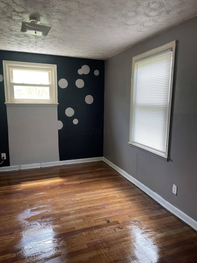 spare room featuring hardwood / wood-style floors and a textured ceiling