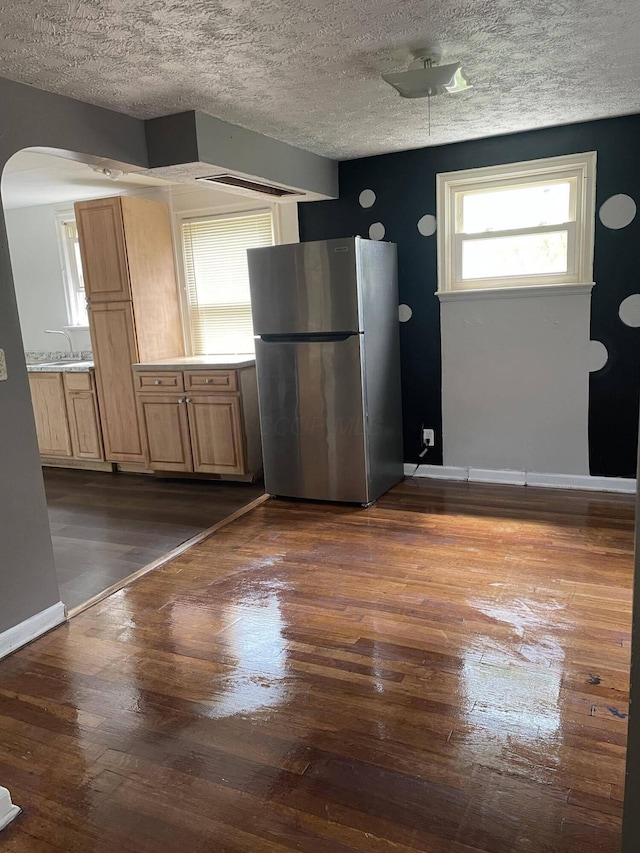 kitchen with stainless steel refrigerator, sink, dark wood-type flooring, and a textured ceiling