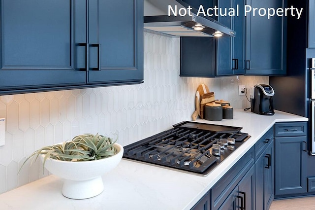 kitchen with gas stovetop, decorative backsplash, light countertops, under cabinet range hood, and blue cabinets