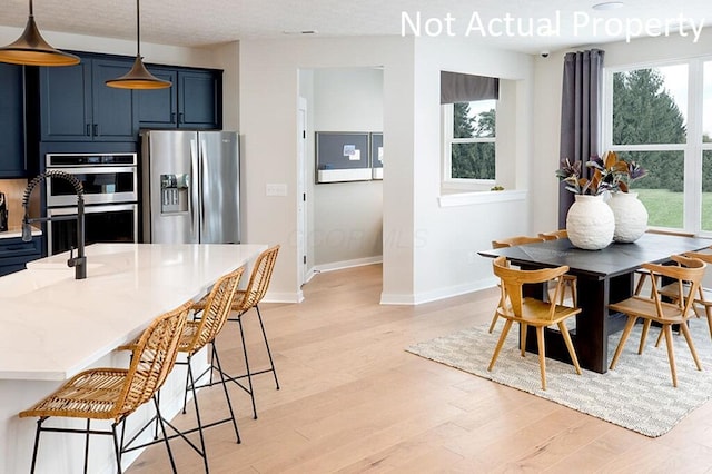 dining room with light wood finished floors, a textured ceiling, and baseboards