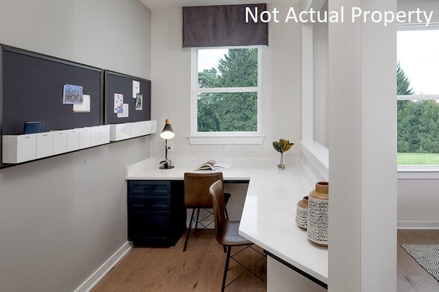 home office featuring baseboards, wood finished floors, and built in desk