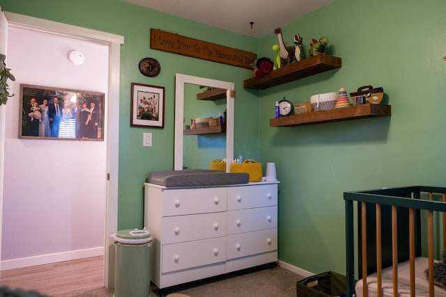 bedroom with a crib and wood-type flooring