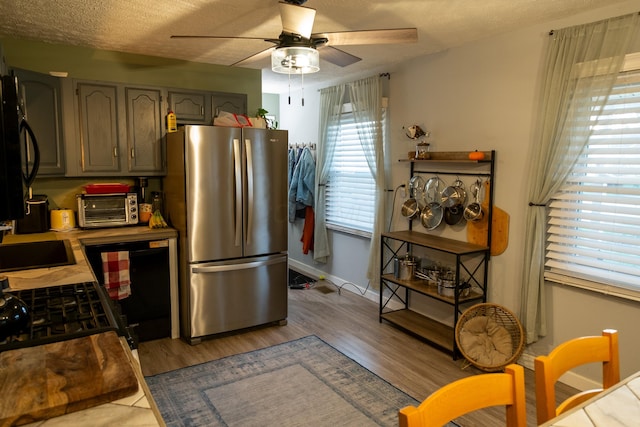 kitchen featuring gray cabinets, light hardwood / wood-style floors, a textured ceiling, and stainless steel refrigerator