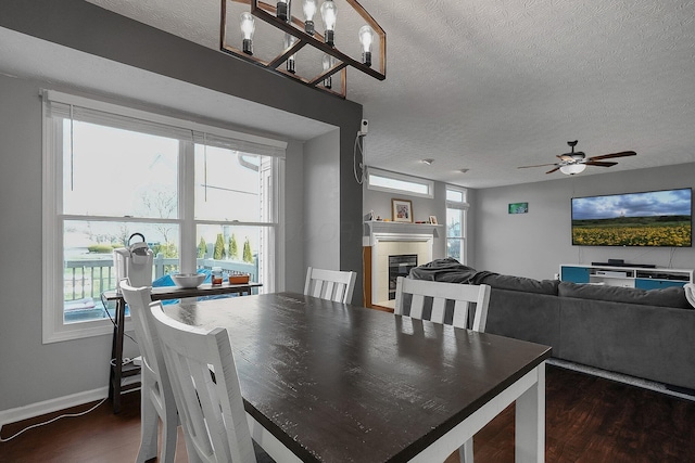 6184 Pirthshire St, Dublin, OH 43016 - dining area featuring a textured ceiling, a glass covered fireplace, a ceiling fan, baseboards, and dark wood-style floors