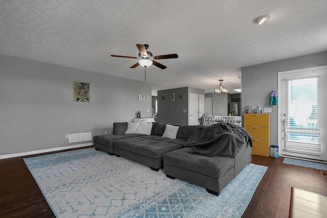 6184 Pirthshire St, Dublin, OH 43016 - living room featuring a textured ceiling, visible vents, wood finished floors, and ceiling fan with notable chandelier