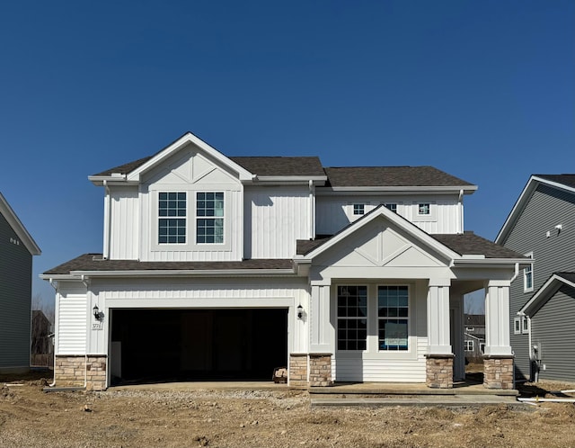 modern inspired farmhouse featuring stone siding, an attached garage, and a shingled roof