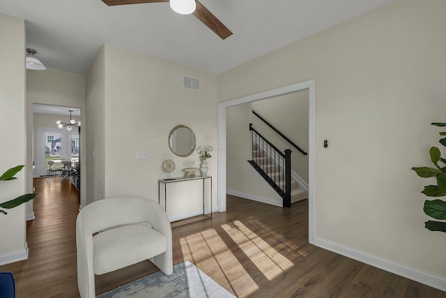 living area featuring dark wood-type flooring and ceiling fan with notable chandelier