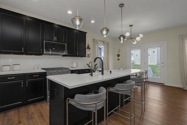 kitchen featuring pendant lighting, dark hardwood / wood-style floors, stainless steel appliances, and an island with sink