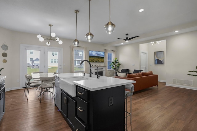 kitchen with a kitchen breakfast bar, ceiling fan, sink, decorative light fixtures, and a center island with sink