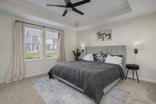 carpeted bedroom with a tray ceiling, ceiling fan, and ornamental molding