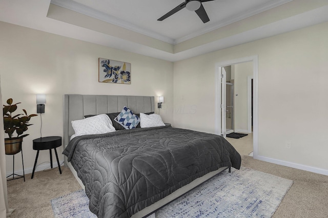 carpeted bedroom with ceiling fan, a raised ceiling, crown molding, and connected bathroom