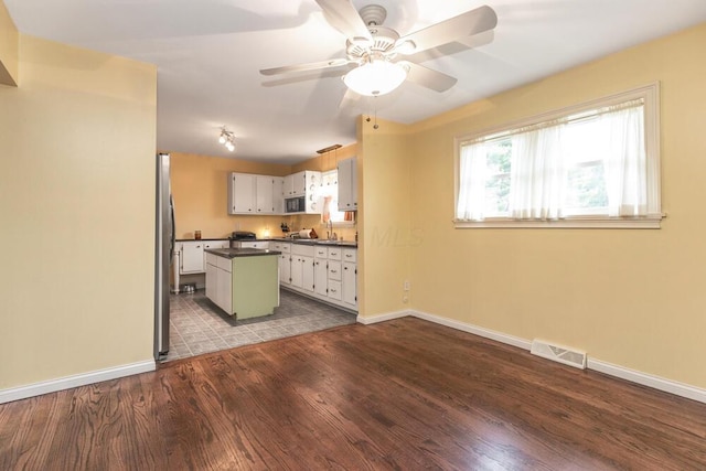 kitchen with dark hardwood / wood-style flooring, ceiling fan, sink, a center island, and white cabinetry