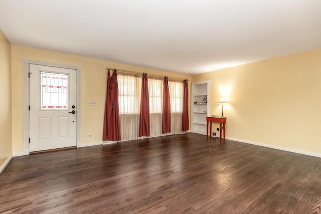 interior space featuring built in shelves, a wealth of natural light, and dark hardwood / wood-style floors