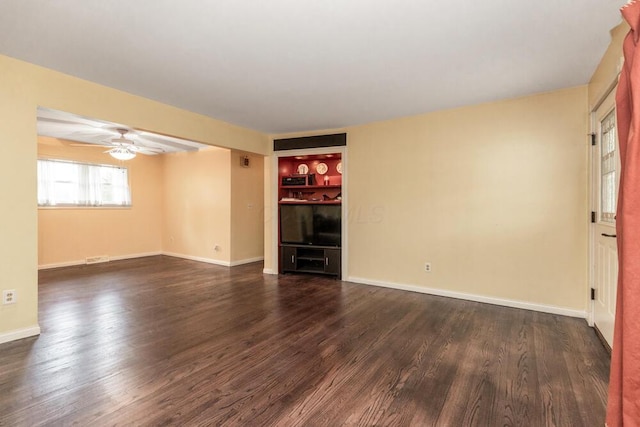 empty room with dark hardwood / wood-style flooring, ceiling fan, and built in features