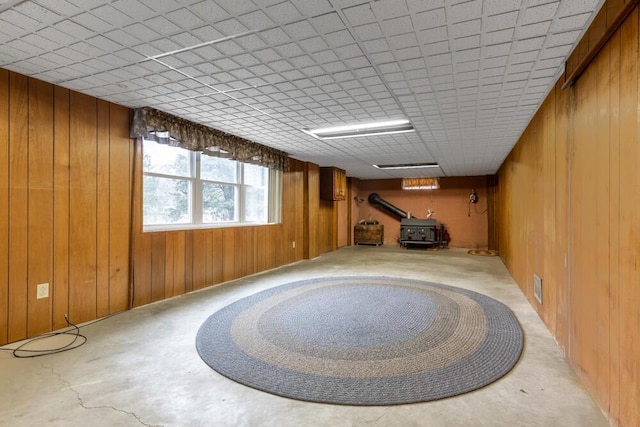 unfurnished room with wood walls and a wood stove