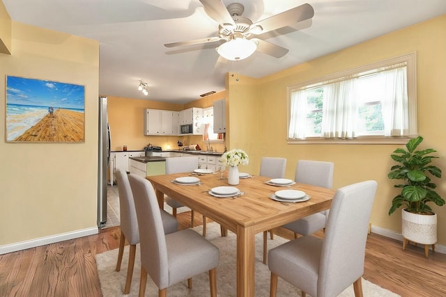 dining room with ceiling fan, light wood-type flooring, and sink