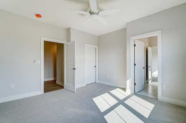 unfurnished bedroom with baseboards, a ceiling fan, and light colored carpet