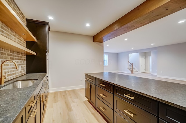 kitchen featuring recessed lighting, a sink, beam ceiling, open shelves, and light wood finished floors