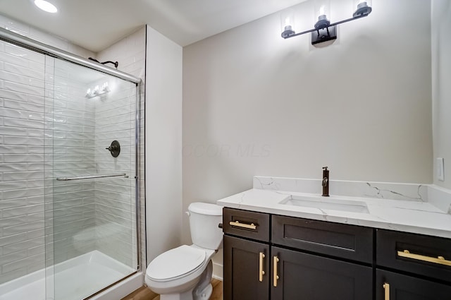 bathroom with a shower stall, toilet, and vanity