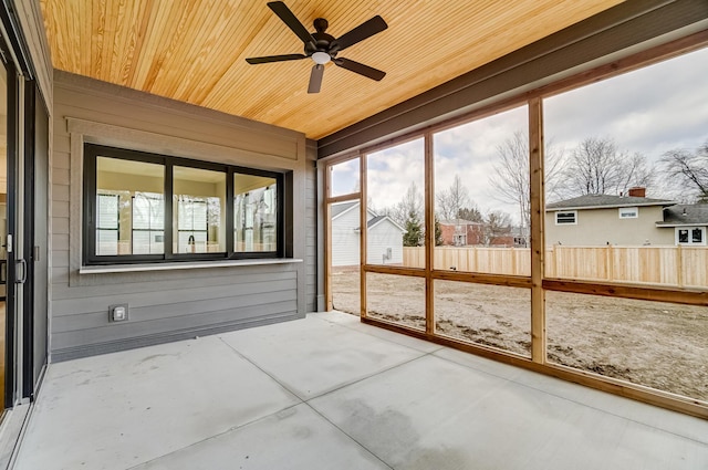 unfurnished sunroom with a ceiling fan and wooden ceiling