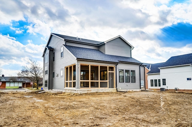 rear view of house featuring central AC, roof with shingles, and a sunroom