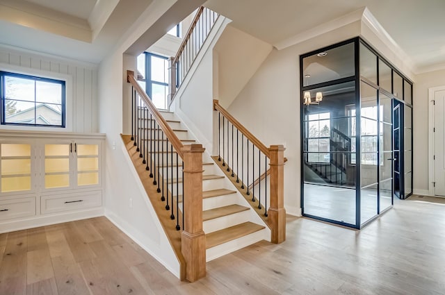 stairway featuring plenty of natural light, crown molding, baseboards, and wood finished floors