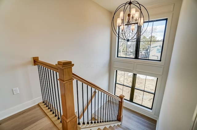 stairs with a chandelier, baseboards, and wood finished floors