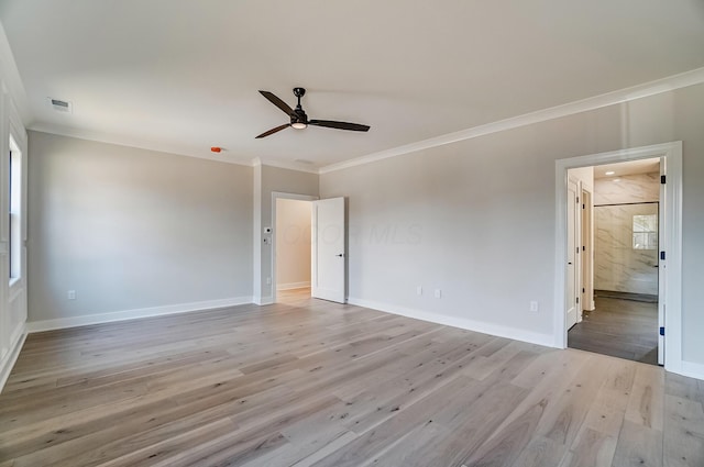 empty room featuring light wood-style floors, baseboards, visible vents, and ornamental molding